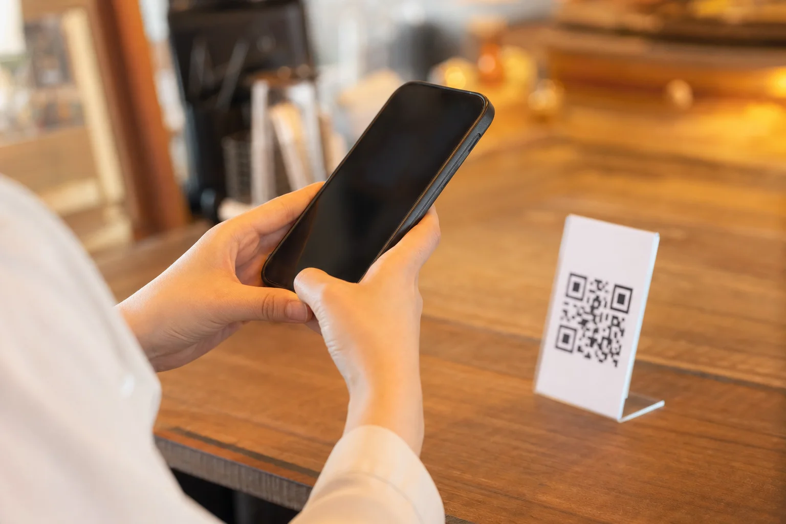 卓上のQRコードにスマートフォンをかざしてGoogle口コミの投稿画面を開くお客様の手元