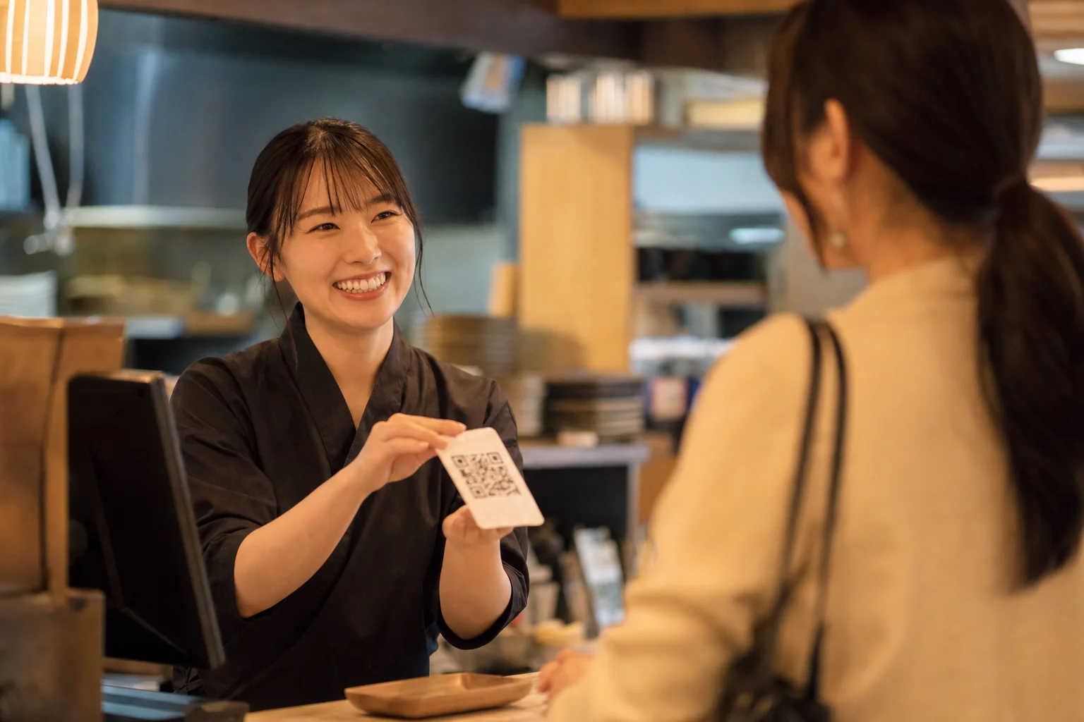会計時にお客さまへ口コミ用QRコードを案内する飲食店スタッフ